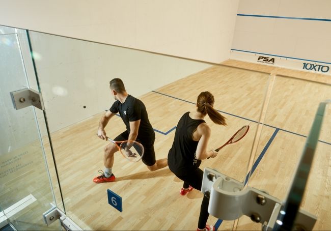 Guests enjoying a game of squash in our glass back courts with hardwood floors.