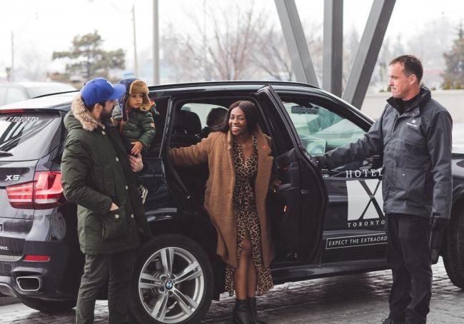 Our complimentary car service makes it convenient for guests to explore nearby attractions in Toronto. This is an image of a family of three entering the front lobby of the hotel.