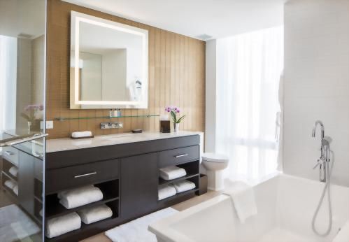 The spacious bathroom with a stand alone bathtub, glass encased shower and city views.