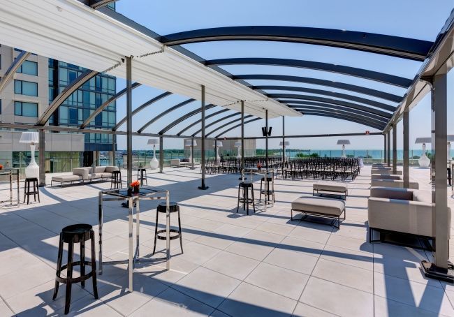 High top tables set up on High Park Terrace with a retractable roof and natural light, overlooking Lane Ontario.